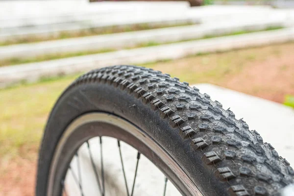 Close up to a black bike tire pattern and blurred green garden at background