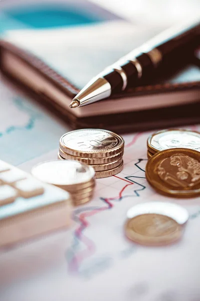 Moedas de close-up com gráfico de linha, caneta e calculadora — Fotografia de Stock