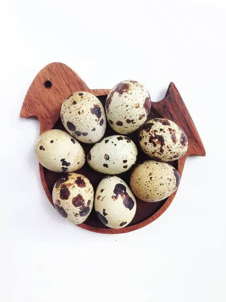 Ovos de codorna no disco em forma de pássaro de madeira no fundo branco — Fotografia de Stock