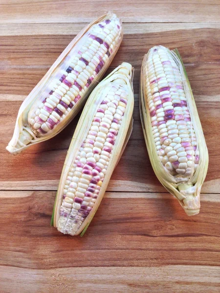 Bílá a fialová kukuřice na dřevěné pozadí — Stock fotografie