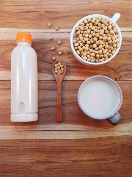 Soy milk in bottle and soy beans with wooden ladle on wooden bac — Stock Photo, Image