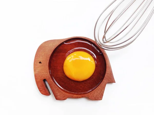 Yolk egg on wooden elephant shaped saucer with egg whisk on whit — Stock Photo, Image