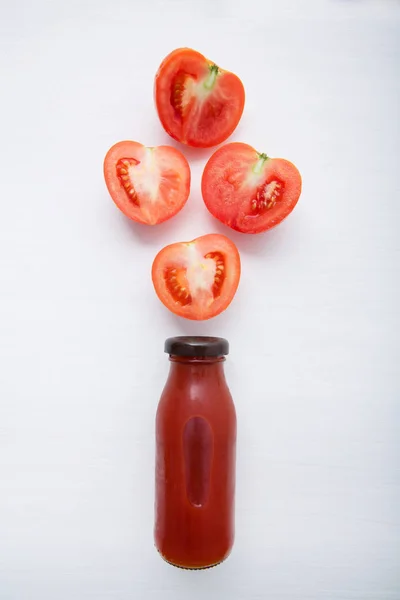 Tomatensaft in der Flasche und frische Tomatenscheiben auf weißem Holz — Stockfoto