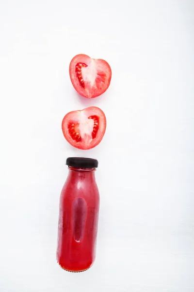 Tomatensaft in der Flasche und frische Tomatenscheiben auf weißem Holz — Stockfoto