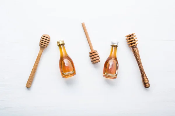 Trempette en bois de miel et petite bouteille de miel sur fond en bois blanc — Photo