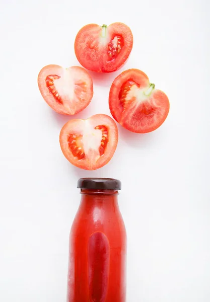 Frische Tomatensaft in der Flasche und frische Tomatenscheiben auf weißem Holzhintergrund. — Stockfoto