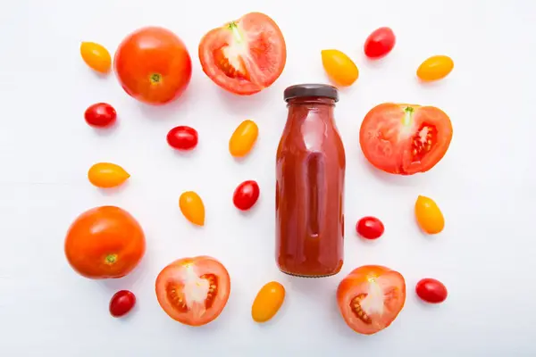 Frische Tomatensaft in der Flasche und frische Tomatenscheiben auf weißem Holzhintergrund. — Stockfoto