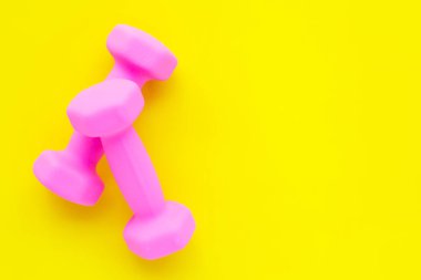Sarı arkaplanda izole edilmiş pembe halterlerin üst görünümü. 