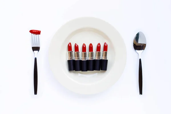 Lipsticks on white dish with fork and spoon on white — Stock Photo, Image