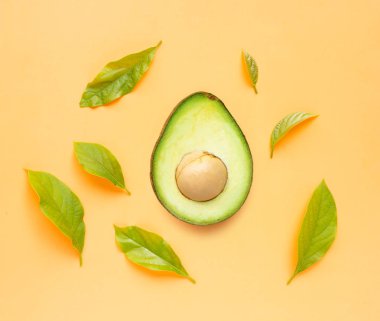 Turuncu arka planda yaprakları olan avokado. 