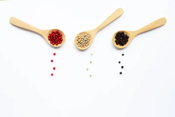 Peppercorns rojos, blancos y negros con cuchara de madera sobre blanco — Foto de Stock