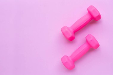 Pembe arka planda izole edilmiş pembe halterlerin üst görünümü.