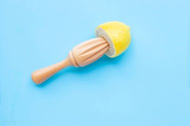 Mavi arka planda ahşap sıkacağı olan taze limon. 