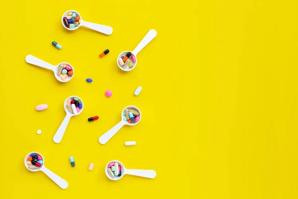 Comprimidos coloridos con cápsulas y pastillas sobre fondo amarillo . — Foto de Stock