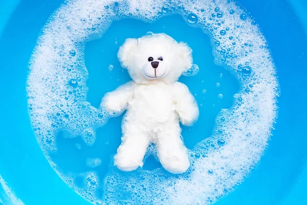 씻기 전에 세제를 사용하여 물을 끓이는 장난감 곰 — 스톡 사진