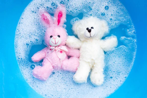 Oyuncak ayı ve oyuncak tavşanı çamaşır deterjanı suyuna batır. — Stok fotoğraf