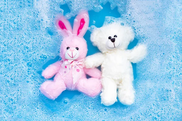 Замочите кроличью куклу с игрушечным плюшевым мишкой в стиральной воде — стоковое фото