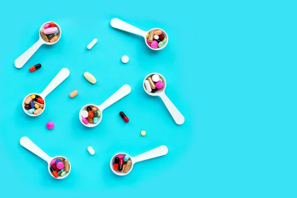 Barevné léky pilulky, tablety a tobolky na modrém pozadí — Stock fotografie
