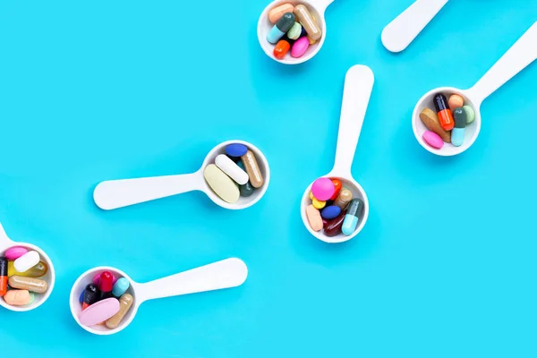 Coloridas píldoras, tabletas y cápsulas medicinales sobre fondo azul — Foto de Stock