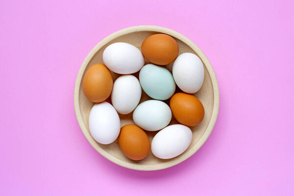 Свежие яйца на розовом фоне. Вид сверху
