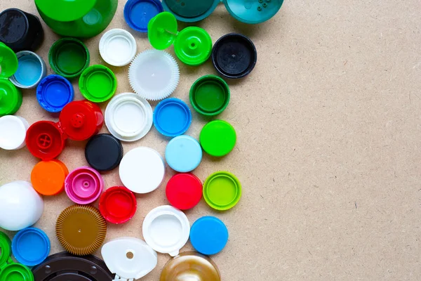 Colorful plastic bottle caps and plastic glass lid on plywood background. Top view