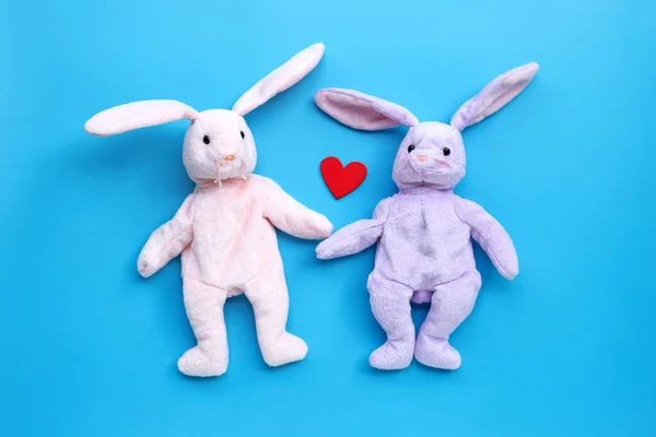 Rabbit toy couple on blue background. Copy space