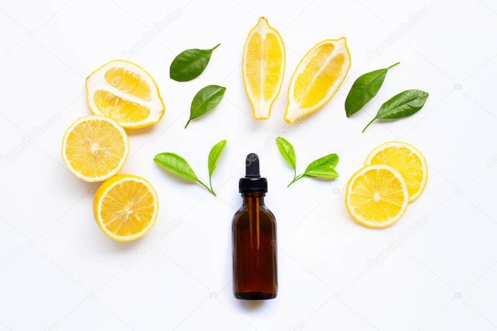 Essential oil with fresh lemon and green leaves on white background.
