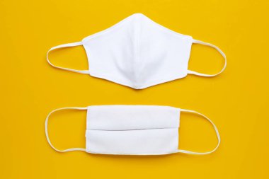  Krem sarısı arka planda el yapımı beyaz kumaş maskeler. Üst görünüm