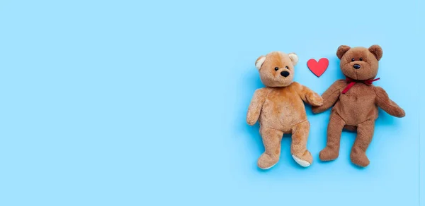 Bear toy couple with heart on blue background. Copy space