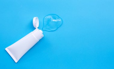 Mavi arka planda beyaz parlak plastik tüplerde kopyalama alanı olan jeli temizle