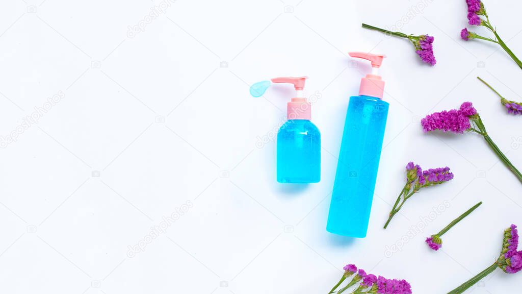 Alcohol hand sanitizer gel in pump bottles on yellow background with static flower, copy space. Hand hygiene corona virus protection concept.