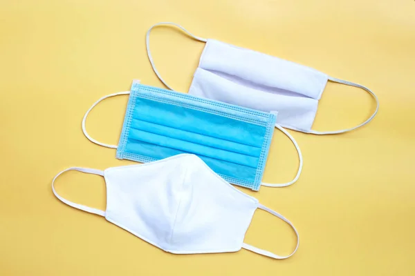 Protective medical mask with cloth masks on yellow background. Top view