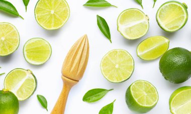 Beyaz arka planda ahşap sıkacağı olan taze limon ve yapraklar..
