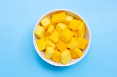 Tropikal meyve, mango küp dilimleri beyaz kasede mavi arka planda. Üst görünüm