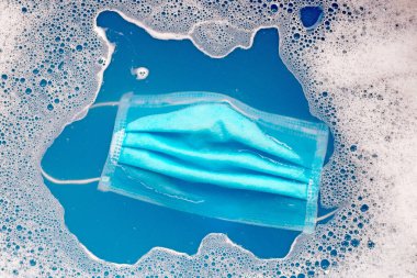 Yıkanmadan önce deterjan içinde koruyucu tıbbi maske. Hijyen koronavirüsü (Covid-19) koruma kavramı