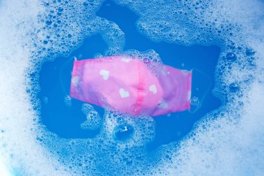 Kumaş maske yıkanmadan önce deterjan suyuna batırılır. Hijyen koronavirüsü (Covid-19) koruma kavramı