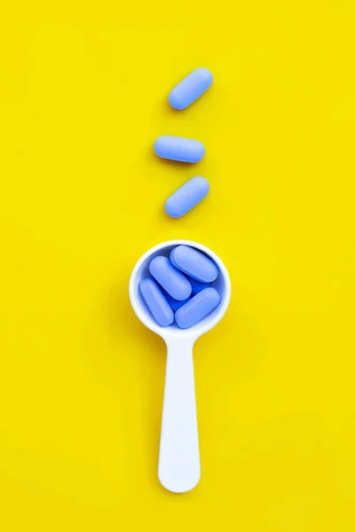 黄色の背景に白いプラスチックスプーン付きの医療用ブルー薬 トップ表示 — ストック写真
