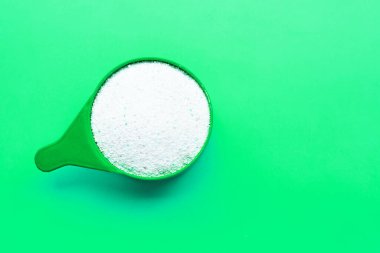 Yeşil arka planda çamaşır tozu ile kepçeyi ölçüyorum. Boşluğu kopyala