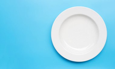Mavi arka planda boş beyaz seramik tabak. Boşluğu kopyala