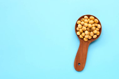 Mavi arka planda tahta kaşıkla soya fasulyesi..