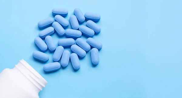 Mavi arka planda beyaz plastik şişeli tıbbi mavi haplar. Boşluğu kopyala