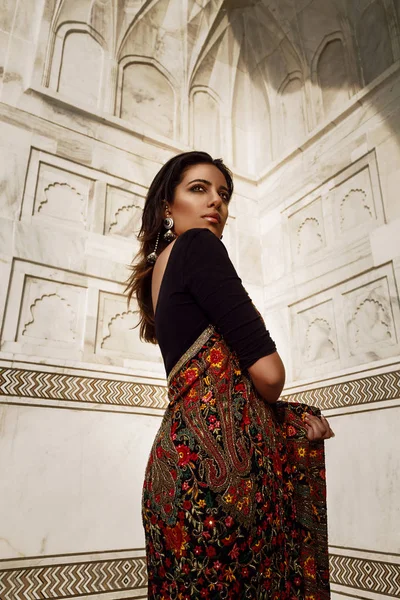 beautiful indian woman in sari at the wall of  taj mahal in india
