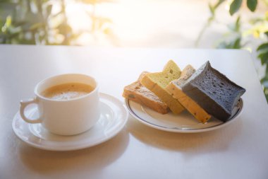 Güneş ışığı ile masada ekmek plakalı beyaz kahve fincanı 