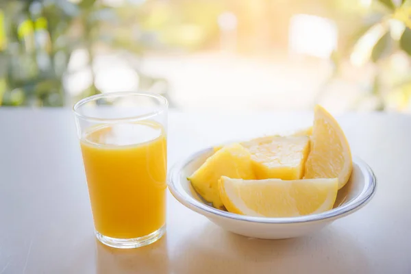 Sklenice pomerančové šťávy na stůl s slunečního světla v poz — Stock fotografie