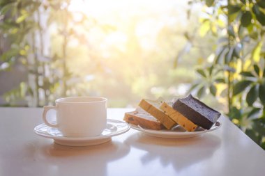 Güneş ışığı ile masada ekmek plakalı beyaz kahve fincanı 