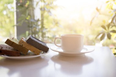 Güneş ışığı ile masada ekmek plakalı beyaz kahve fincanı 