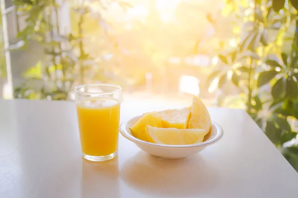 Sklenice pomerančové šťávy na stůl s slunečního světla v poz — Stock fotografie