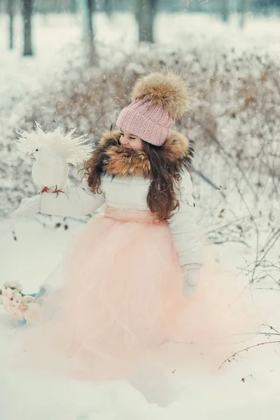 Snowy winter and a girl in a cap with doves — Stock Photo, Image