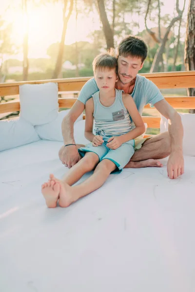 Filho com seu pai em um sofá de madeira — Fotografia de Stock