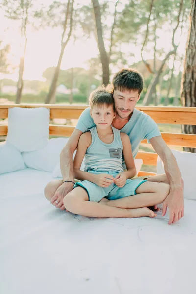 Filho com seu pai em um sofá de madeira — Fotografia de Stock